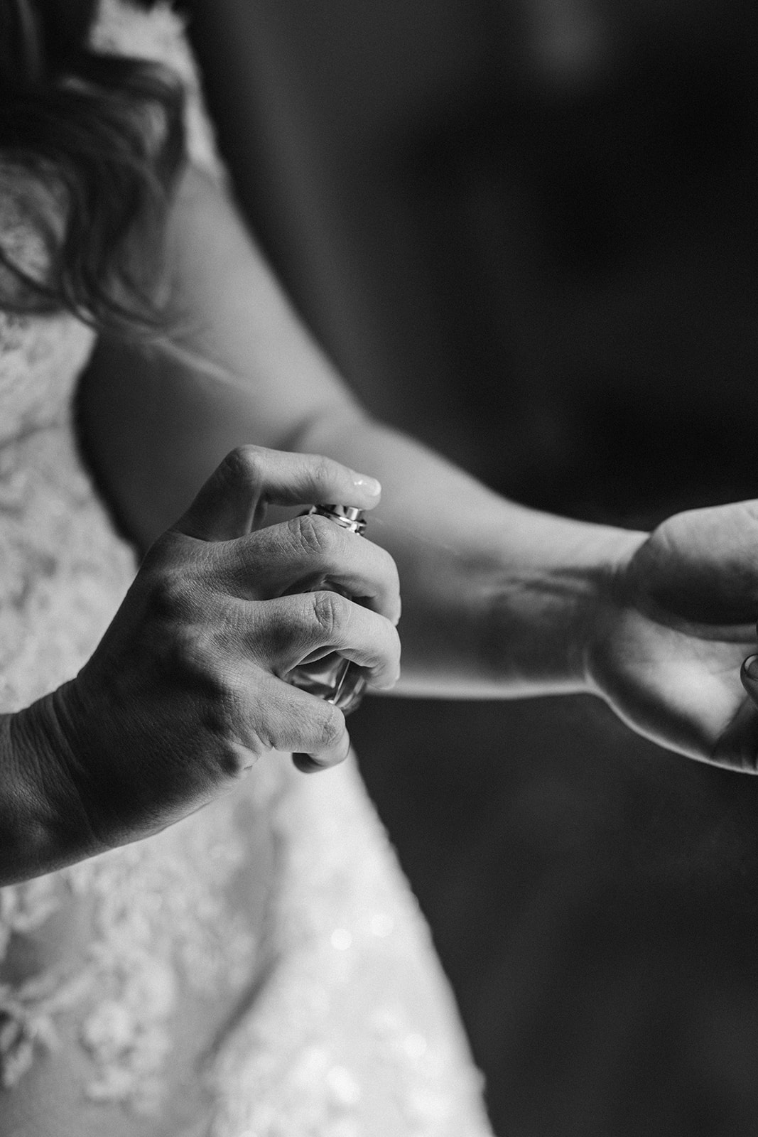 closeup of a bride's hand holding and spraying perfume onto her wrist
