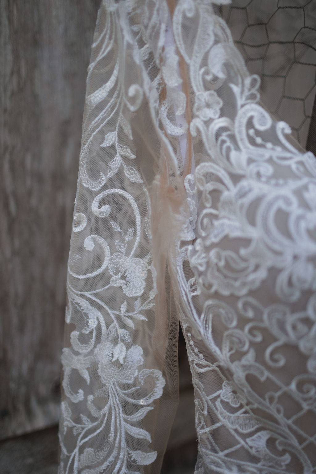 The edge of a bride's dress showing the lace of the left sleeve
