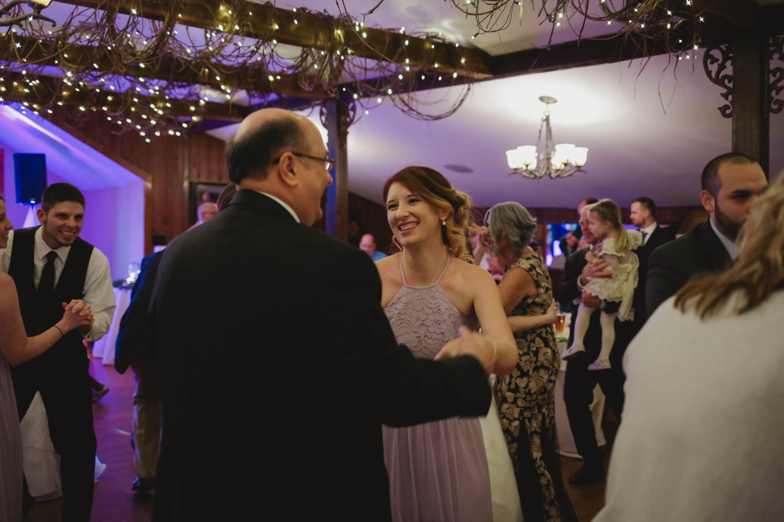 a bridesmaid dancing with the father of the bride
