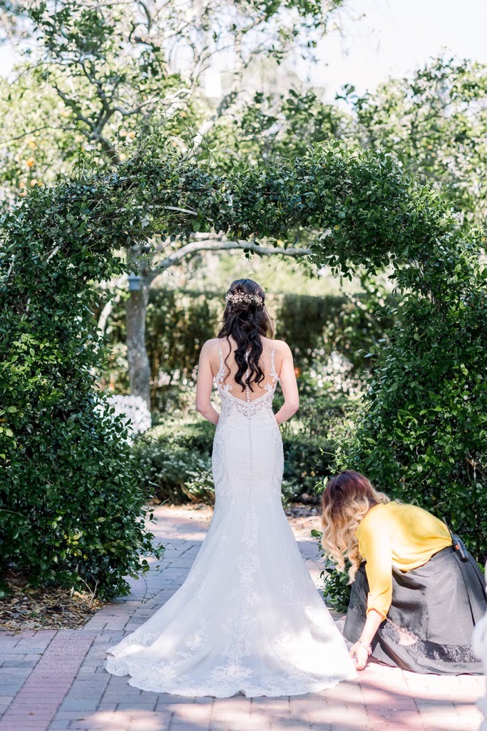 a wedding coordinator adjusts a bride's dress hem
