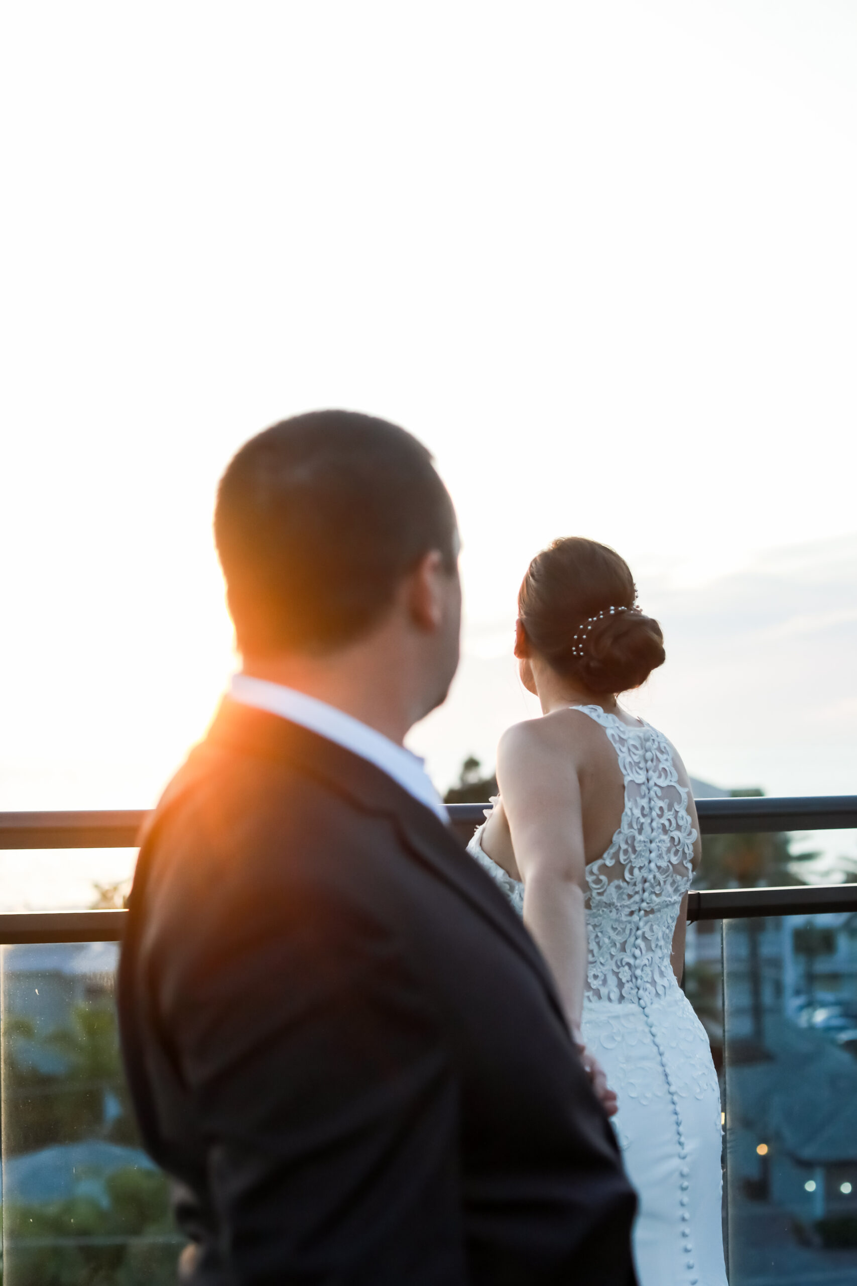 a bride in the background looking away from the camera and a groom in the foreground holding the bride's hand looking at her